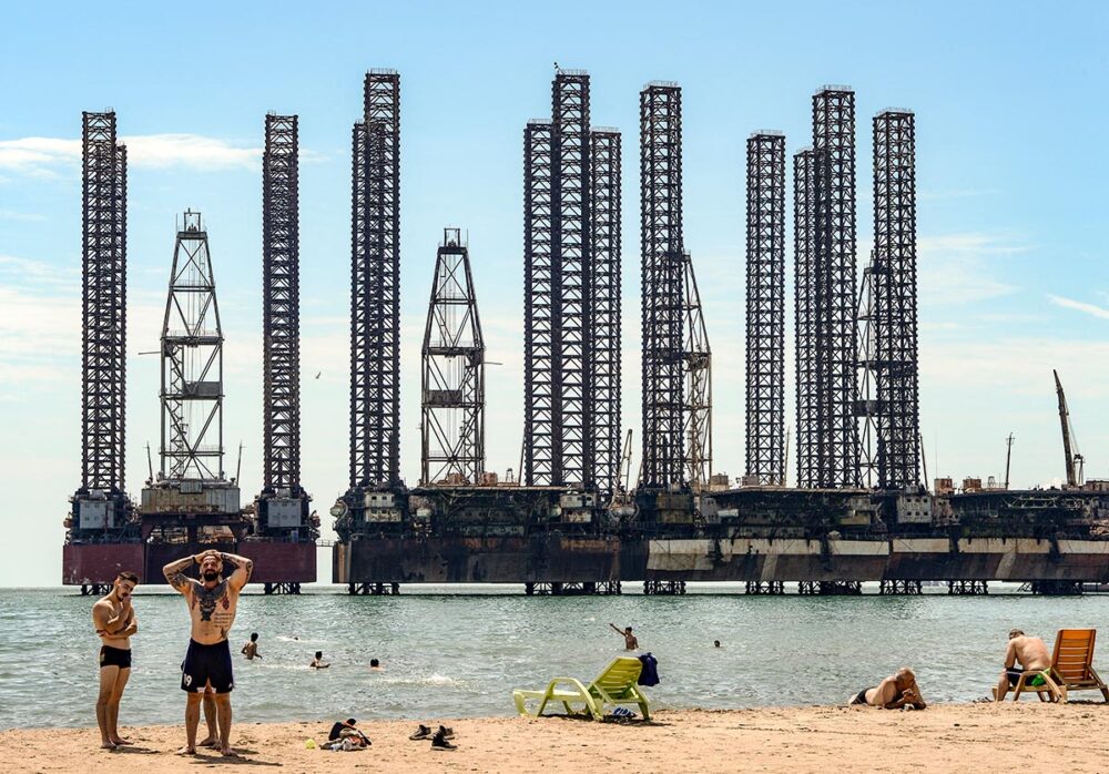 COP29 : les recours climatiques influent-ils sur les négociations ? - Photo : des gens se baignent dans la Mer Caspienne à Bakou, Azerbaïdjan. En arrière-plan : des barges pétrolières.