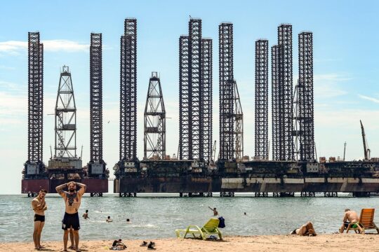 COP29 : les recours climatiques influent-ils sur les négociations ? - Photo : des gens se baignent dans la Mer Caspienne à Bakou, Azerbaïdjan. En arrière-plan : des barges pétrolières.