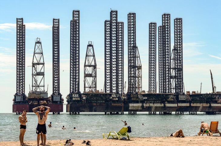 COP29 : les recours climatiques influent-ils sur les négociations ? - Photo : des gens se baignent dans la Mer Caspienne à Bakou, Azerbaïdjan. En arrière-plan : des barges pétrolières.