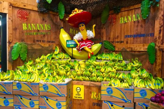 Procès Chiquita - Photo : un stand promotionnel composé uniquement de bananes Chiquita. Tout en haut trône la mascotte de la marque. A l'avant du stand, un gros bouton et un écriteau où il est inscrit 