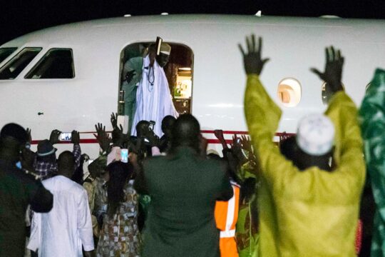 En Gambie, un tribunal spécial a été conçu pour juger les crimes commis sous la dictature de Yahya Jammeh. Se pose maintenant la question de son financement. Photo : en 2017, Jammeh s'apprête à quitter la Gambie pour la Guinée Équatoriale. Il sourit et salut la foule à la porte d'un avion.