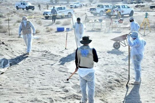 UNITAD teams on the ground in Iraq, helping to find mass graves where victims of the Islamic State organisation were buried. Photo: investigators and technicians (one wearing a waistcoat bearing the United Nations logo) work on a mass grave site.