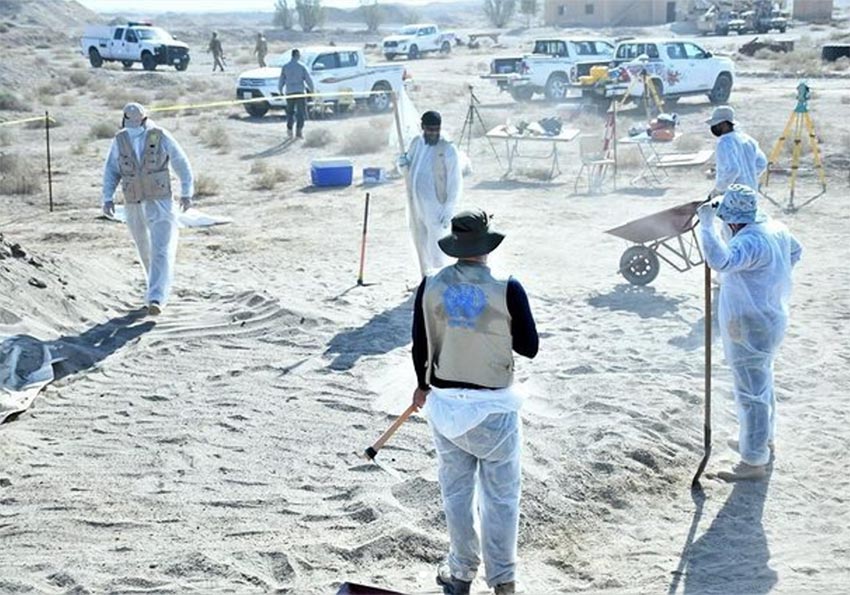 Les équipes d'UNITAD sur le terrain en Irak, participant à la recherche de fosses communes où furent enterrées des victimes de l'organisation État Islamique. Photo : des enquêteurs et techniciens (dont un porte un gilet affichant logo des Nations Unies) travaillent sur un site de fosses communes.