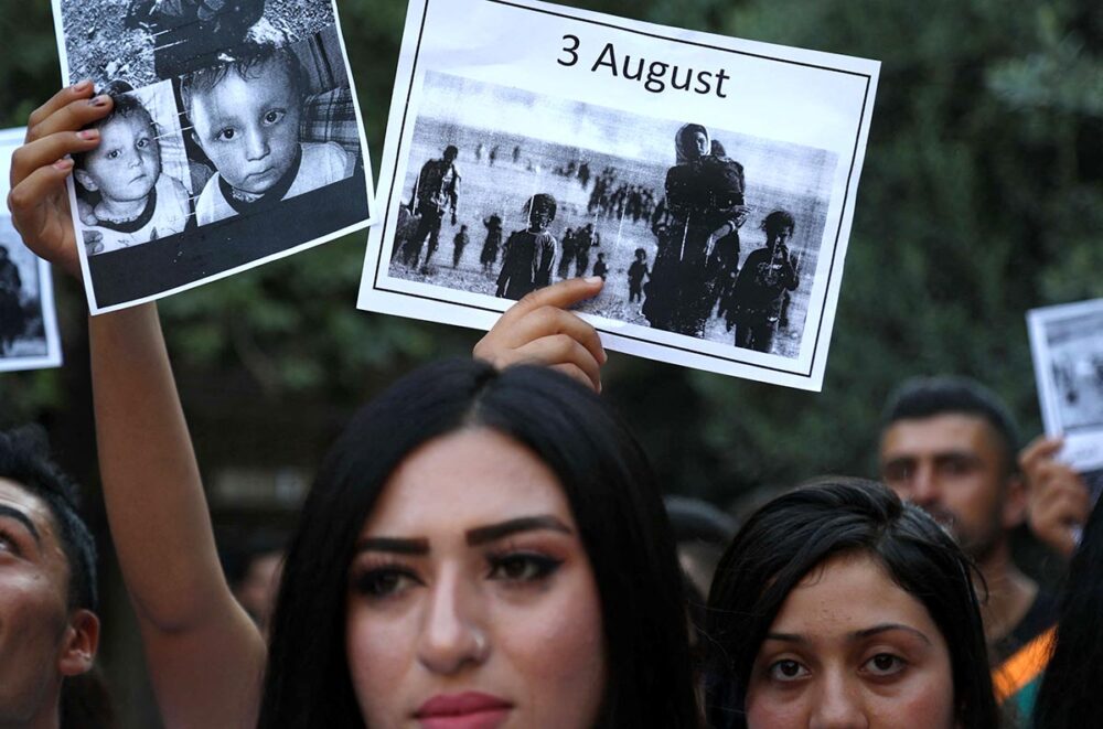 Génocide des Yézidis - Photo : en Irak, des femmes yézidies brandissent des pancartes commémorant l'invasion de leur région par le groupe État islamique (EI) en 2014.