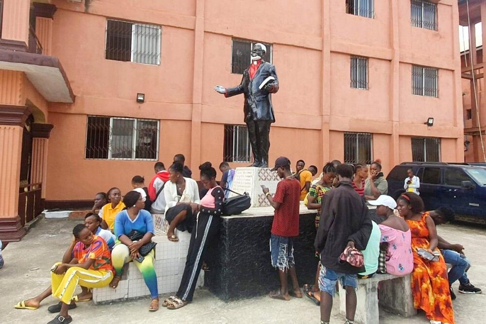 In Liberia, a statue of Prince Y. Johnson has been erected in front of apartment blocks. A group of young people surround it, some sitting on the pedestal.