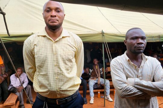 In the Kasai region of the Democratic Republic of Congo, the verdict is confirmed on appeal for two defendants, former Kamwina Nsapu militiamen, in a trial for war crimes. Photo: The two defendants pose under a tent set up during a mobile court hearing in the village where the crimes took place.