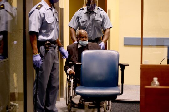 Mécanisme résiduel de l'ONU (MTPI) - Photo : Félicien Kabuga, dans un fauteuil roulant, est accompagné par deux policiers lors de son procès, pris en charge par le Mécanisme, pour son implication dans le génocide au Rwanda.