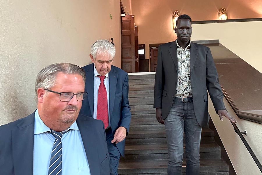 Former child soldier Liah Diu Gatkuoth walks down a staircase, accompanied by his lawyers, at StockHolm Court (Sweden).