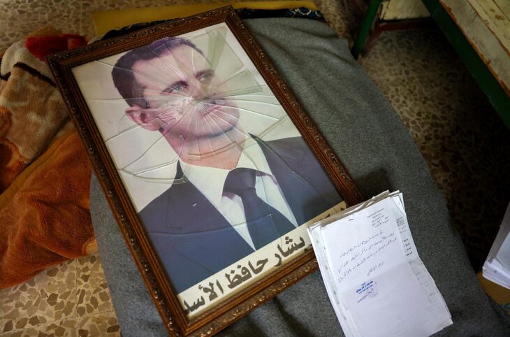 International justice for Bashar al-Assad's crimes in Syria. Photo: Broken portrait of Bashar al-Assad next to documents.