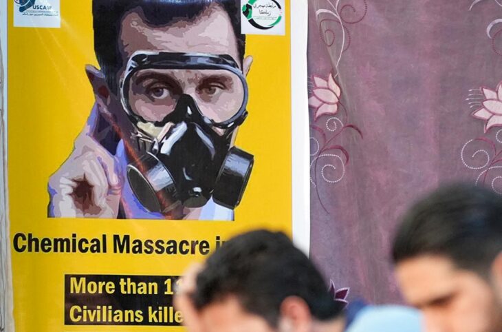 Mandat d'arrêt émis par la justice française contre Bachar Al-Assad (président syrien), en relation avec les attaques chimiques de 2013 en Syrie. Photo : poster dans une rue syrienne montrant Al-Assad avec un masque à gaz sur le visage.