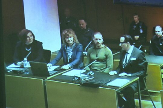 Trial of Russian soldier Voislav Torden in Finland for possible war crimes committed in Ukraine. Torden sits on a television screen during his trial, surrounded by his lawyers.